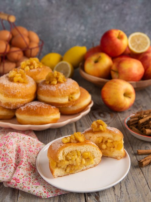 Bomboloni alle mele caramellate tagliati a meta con ripieno abbondante e superficie zuccherata