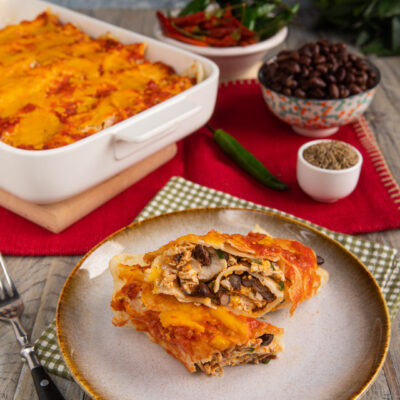Enchiladas di pollo e formaggio farcite con fagioli neri, coperte di salsa e formaggio filante gratinato