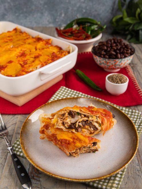 Enchiladas di pollo e formaggio farcite con fagioli neri, coperte di salsa e formaggio filante gratinato