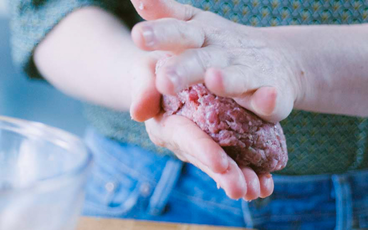 Mani che modellano un disco di carne macinata cruda per formare un hamburger