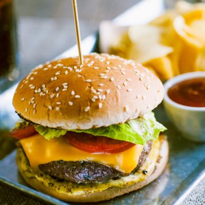 Hamburger con burger di manzo, cheddar fuso, pomodoro, lattuga e senape nel panino ai sesami