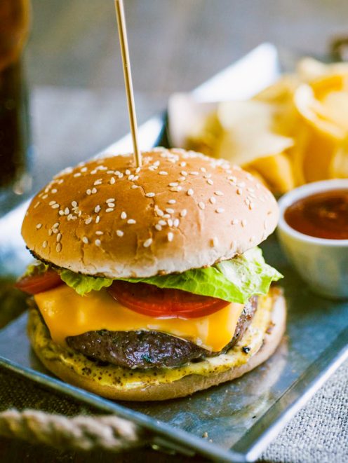 Hamburger con burger di manzo, cheddar fuso, pomodoro, lattuga e senape nel panino ai sesami