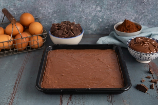 Impasto al cacao steso in modo uniforme sulla teglia, pronto per la cottura