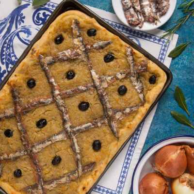Pissaladière appena sfornata con acciughe a griglia, olive nere e cipolla caramellata