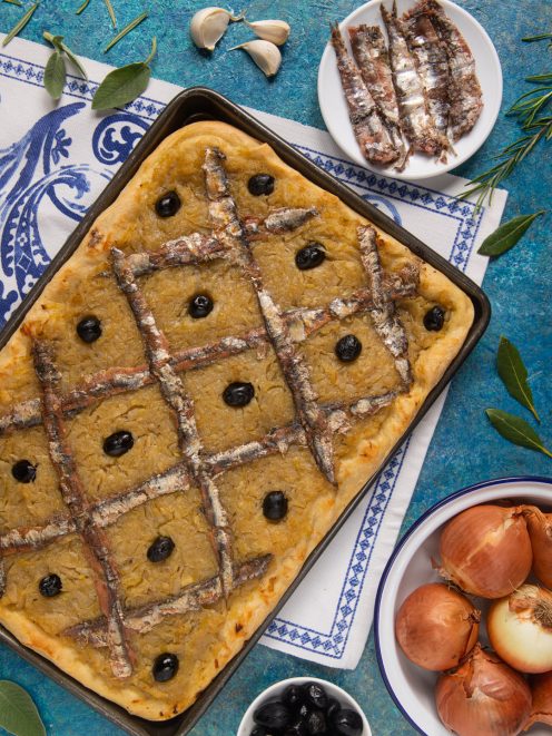 Pissaladière appena sfornata con acciughe a griglia, olive nere e cipolla caramellata