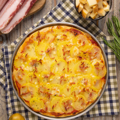 Pizza con patate e pancetta croccante ricoperta di formaggio filante e rosmarino