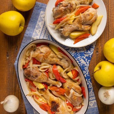 Pollo al sidro con mele, cosce dorate su peperoni e cipolle stufate in pirofila e piatto