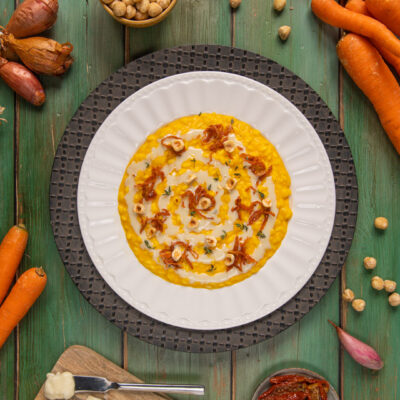 Risotto con carote e gorgonzola guarnito a spirale con scalogno croccante e nocciole tostate