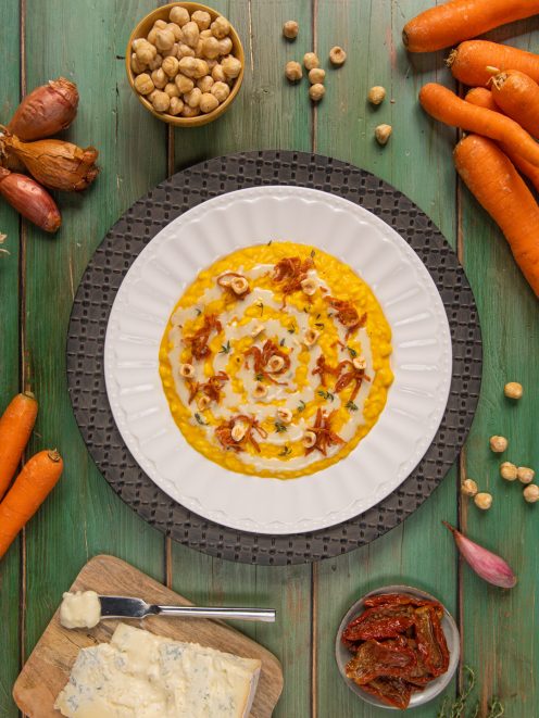 Risotto con carote e gorgonzola guarnito a spirale con scalogno croccante e nocciole tostate