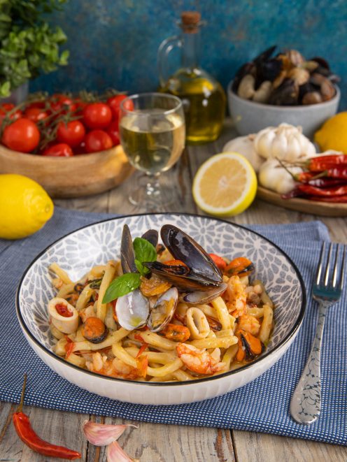 Scialatielli allo scoglio con cozze aperte, vongole, gamberi e calamari, guarniti con basilico fresco