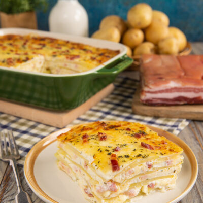 Sformato di patate a strati con pancetta e formaggio filante, servito a fetta