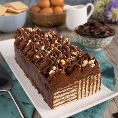Torta di biscotti al cioccolato a strati, ricoperta di ganache e ciuffi di crema con granella