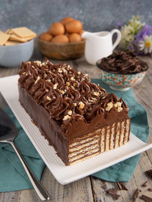 Torta di biscotti al cioccolato a strati, ricoperta di ganache e ciuffi di crema con granella