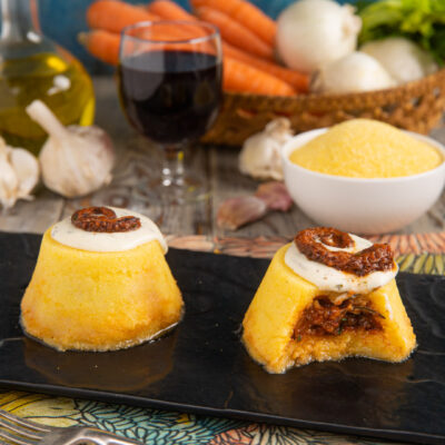 Tortini di polenta ripieni di ragù di polpo, aperti a mostrare il cuore e nappati con crema alle erbe