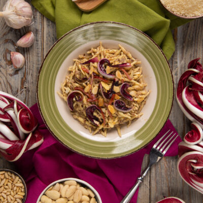Trofie al pesto di radicchio e speck guarnite con petali di radicchio crudo e mandorle a lamelle