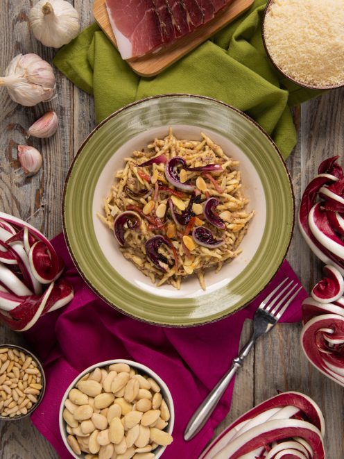 Trofie al pesto di radicchio e speck guarnite con petali di radicchio crudo e mandorle a lamelle