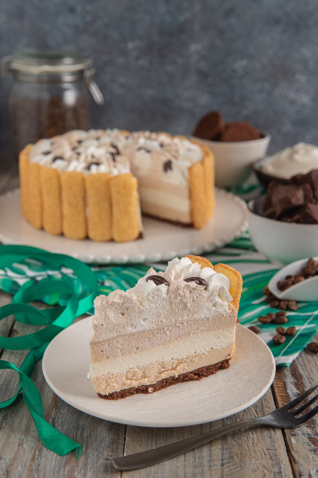 Fetta di charlotte al caffè con strati di crema e savoiardi, guarnita con panna e chicchi di caffè
