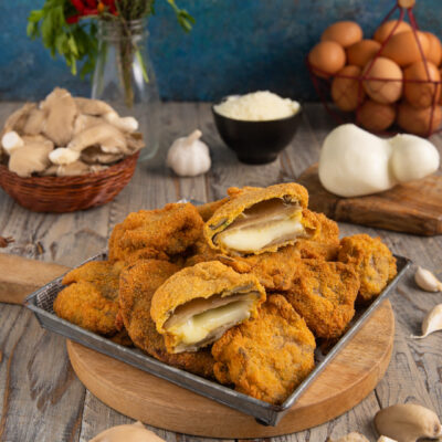 Cotolette di funghi ripiene impanate e fritte, tagliate a metà con cuore filante di mozzarella
