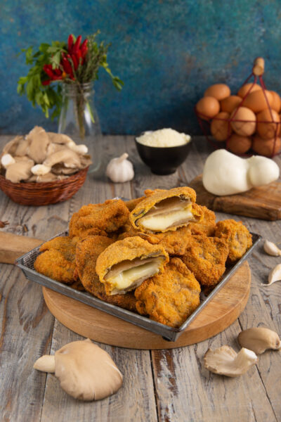 Cotolette di funghi ripiene impanate e fritte, tagliate a metà con cuore filante di mozzarella
