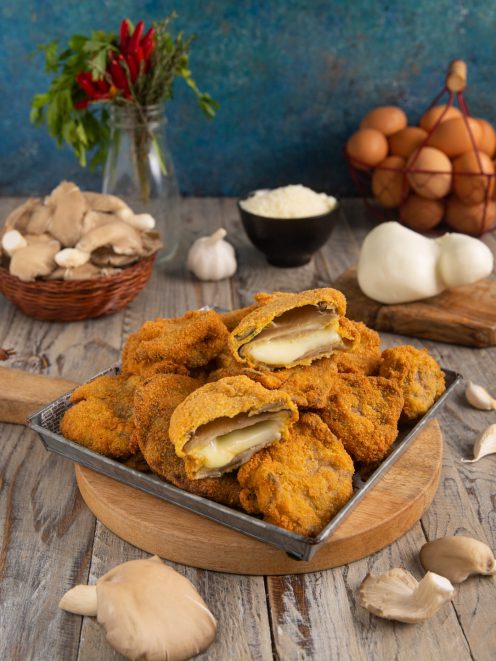 Cotolette di funghi ripiene impanate e fritte, tagliate a metà con cuore filante di mozzarella