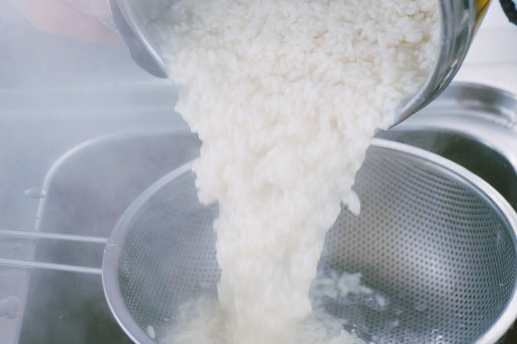Riso scolato al dente sciacquato sotto acqua fredda per sgranare i chicchi