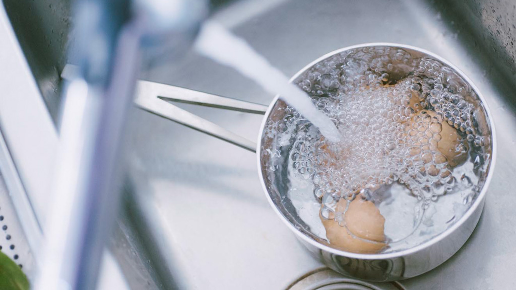 Uova sode in raffreddamento sotto l'acqua fredda