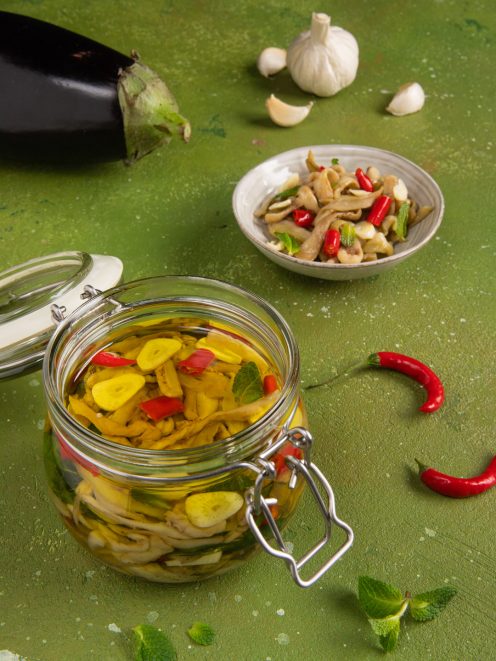 Melanzane sott'olio in barattolo di vetro con peperoncino, aglio e foglie di menta