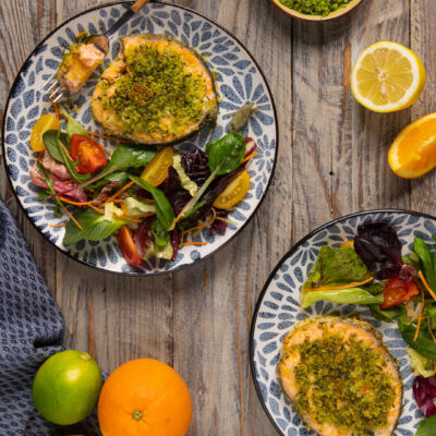 Salmone al forno con crosta di erbe servito con insalata mista, agrumi e verdure fresche a fianco