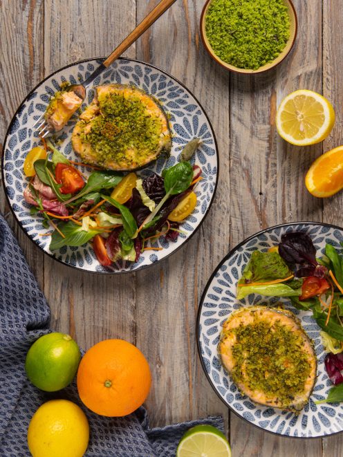 Salmone al forno con crosta di erbe servito con insalata mista, agrumi e verdure fresche a fianco