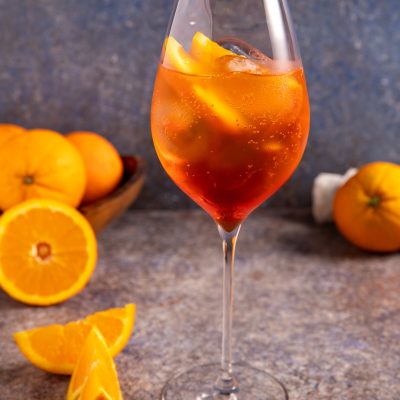 Spritz cocktail con ghiaccio e spicchi d'arancia, servito in calice da vino