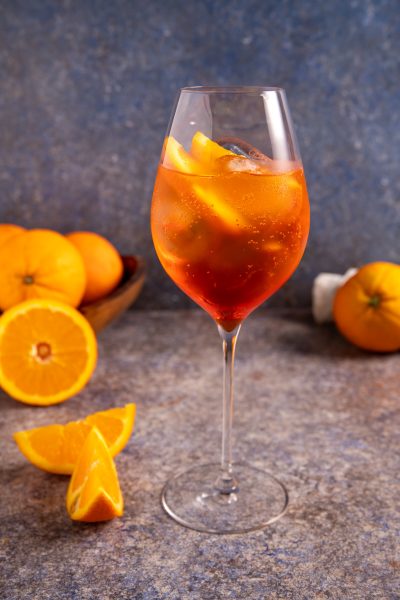Spritz cocktail con ghiaccio e spicchi d'arancia, servito in calice da vino