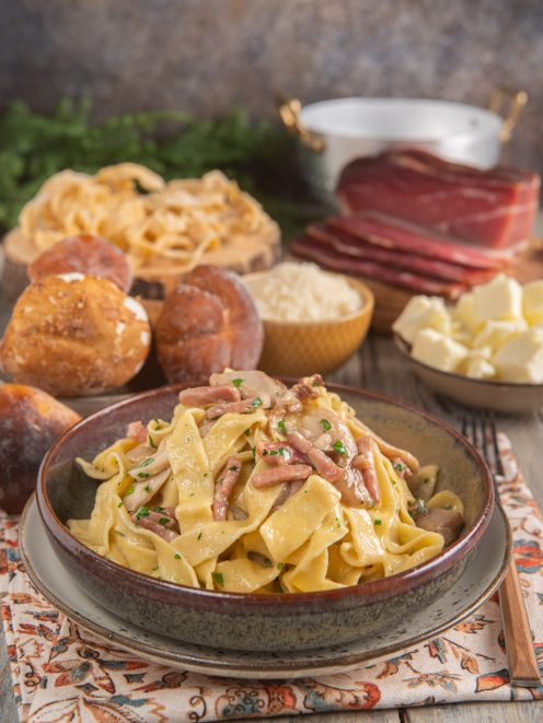 Tagliatelle con speck e funghi condite con prezzemolo tritato