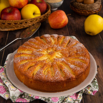 Torta di mele senza burro dorata con fette di mela disposte a raggiera e zucchero a velo