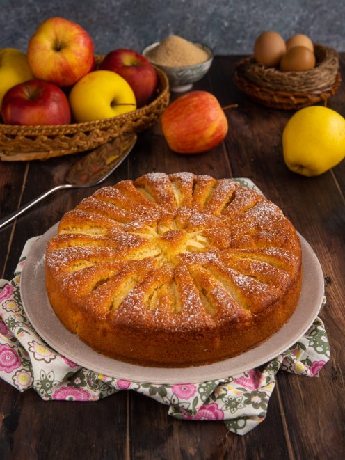 Torta di mele senza burro dorata con fette di mela disposte a raggiera e zucchero a velo