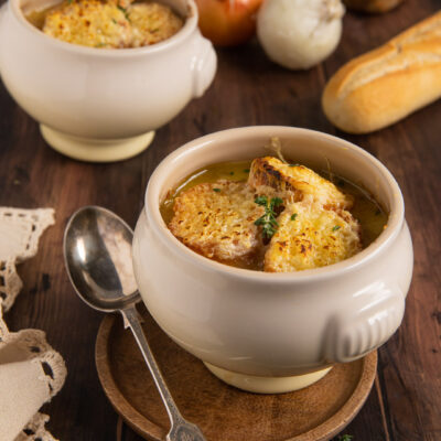 Zuppa di cipolle servita con crostoni di pane gratinati al formaggio e timo fresco