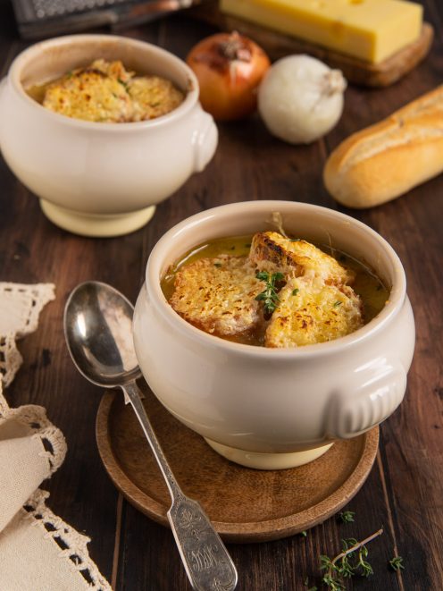 Zuppa di cipolle servita con crostoni di pane gratinati al formaggio e timo fresco