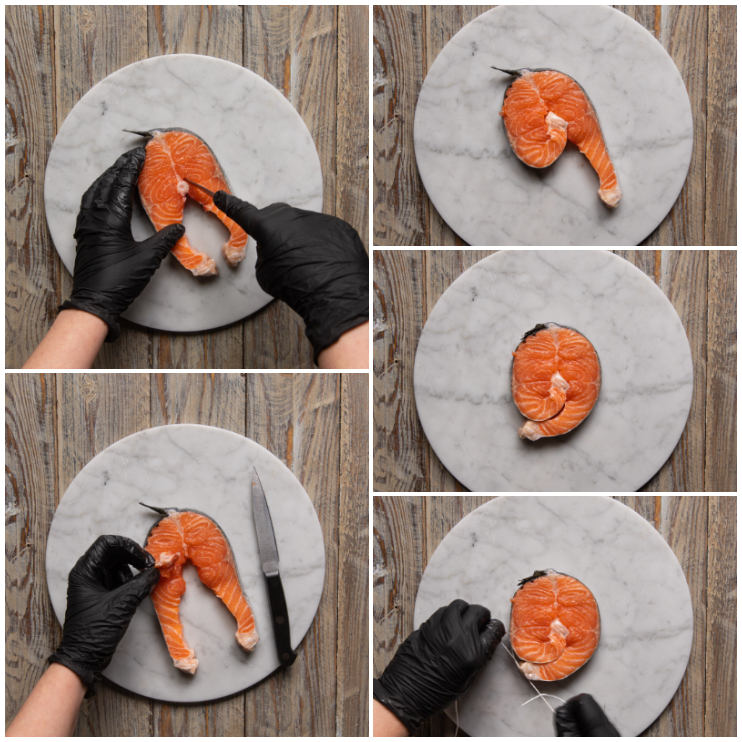 Trancio di salmone modellato a medaglione e legato con spago da cucina su tagliere di marmo
