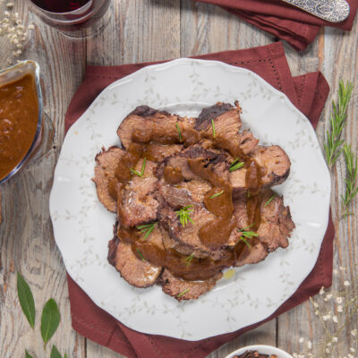 Brasato al Barolo affettato e nappato con salsa scura, guarnito con aghi di rosmarino