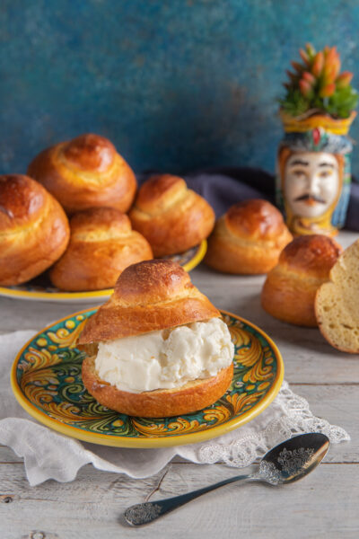 Brioscia col tuppo farcita di gelato alla panna con altre brioches sullo sfondo