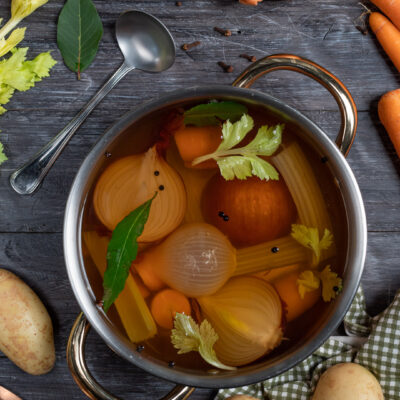 Brodo di verdure con cipolle, carote, sedano e alloro in cottura