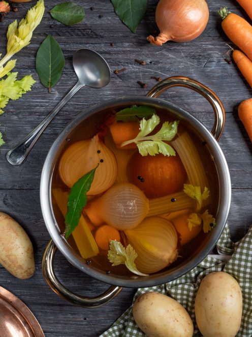 Brodo di verdure con cipolle, carote, sedano e alloro in cottura