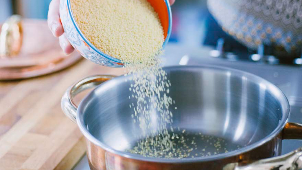Couscous tostato a secco in tegame mentre lo zafferano si stempera nel brodo caldo