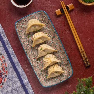 Dumpling disposti in fila e guarniti con erba cipollina tritata