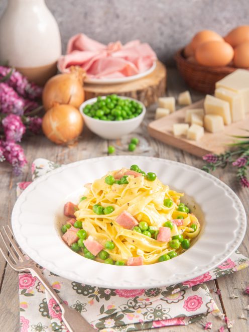 Fettuccine alla papalina con piselli verdi e cubetti di prosciutto cotto, condite con pepe nero