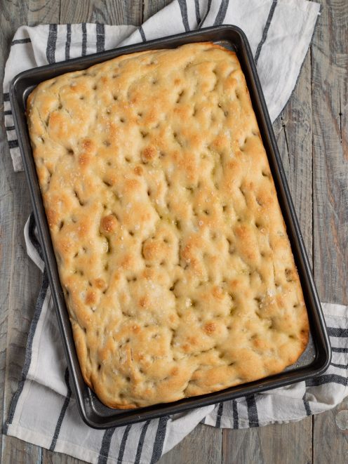 Focaccia appena sfornata con fossette, olio e sale grosso in superficie