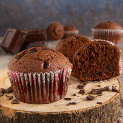Muffin al cioccolato con cuore morbido e gocce, tagliato a meta accanto a pezzi di cioccolato