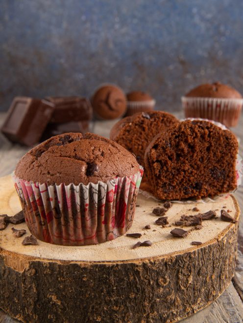 Muffin al cioccolato con cuore morbido e gocce, tagliato a meta accanto a pezzi di cioccolato