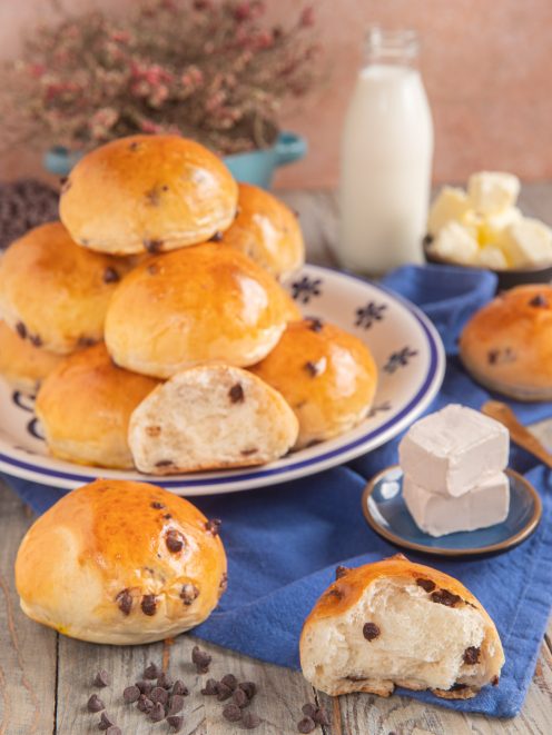 Panini al latte con gocce di cioccolato impilati su un piatto, uno aperto a mostrare la mollica soffice