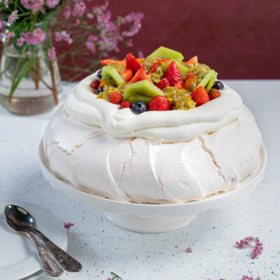 Pavlova con meringa soffice guarnita di fragole, kiwi, mirtilli e frutto della passione