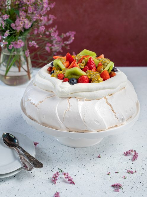 Pavlova con meringa soffice guarnita di fragole, kiwi, mirtilli e frutto della passione